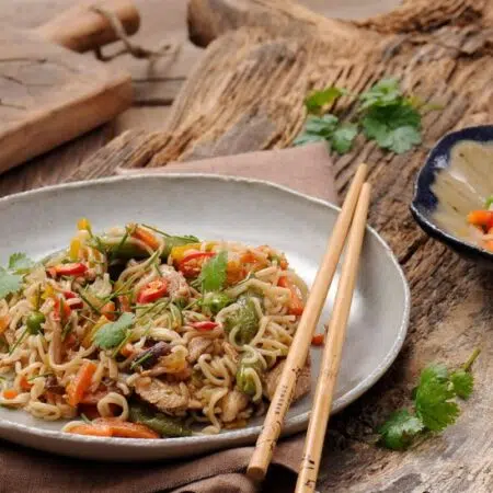 oriental chicken with vegetable and noodles served on a plate